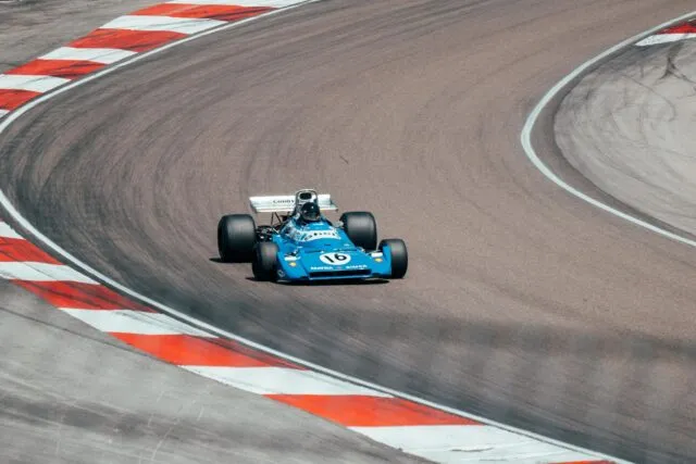 Monopost de Formula 1 în viteză pe un circuit, cu tribunele pline de spectatori în fundal