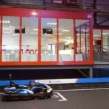 Karturi colorate în viteză pe o pistă de karting acoperită, delimitată de anvelope de protecție