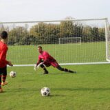 Jucători de fotbal aliniați pe teren în timpul unei faze de atac, cu arbitrul asistent pe margine